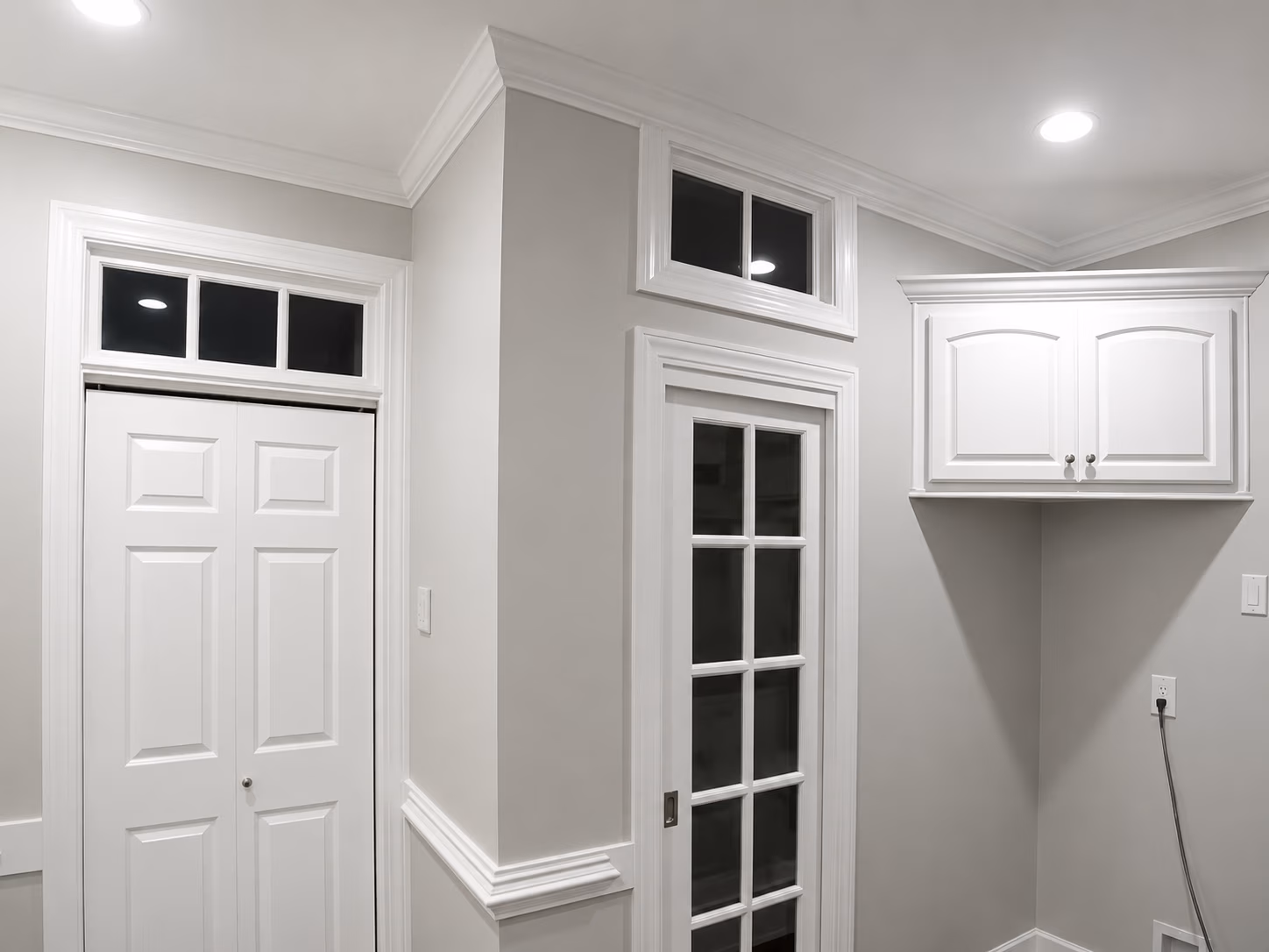 Interior corner with closed white double door, glass-paneled door, upper window, and wall cabinet.